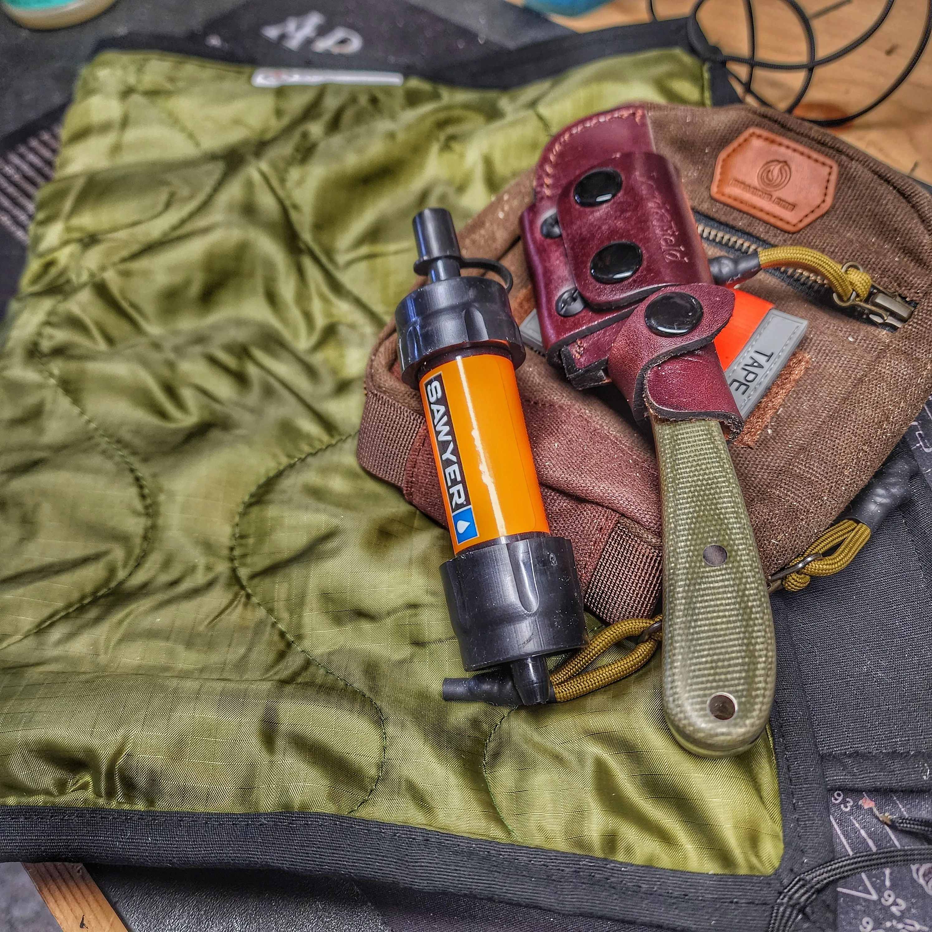 Woobie Hank: Insulated with USGI poncho-liner, serves as a large rag, knee pad, and adventure companion tool.